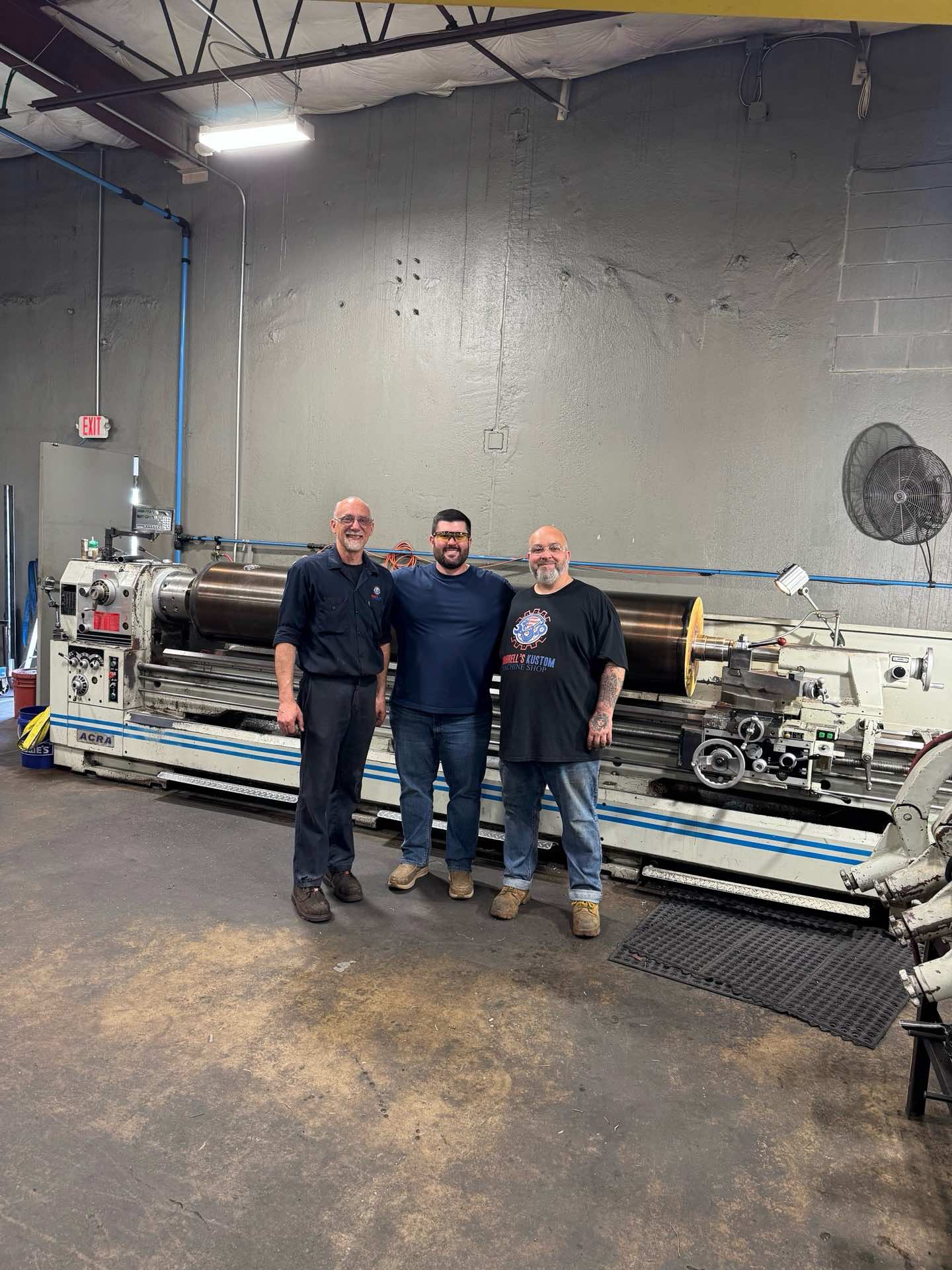 Three Kimbrell team members in front of a long-bed lathe inside the Garland, Texas facility