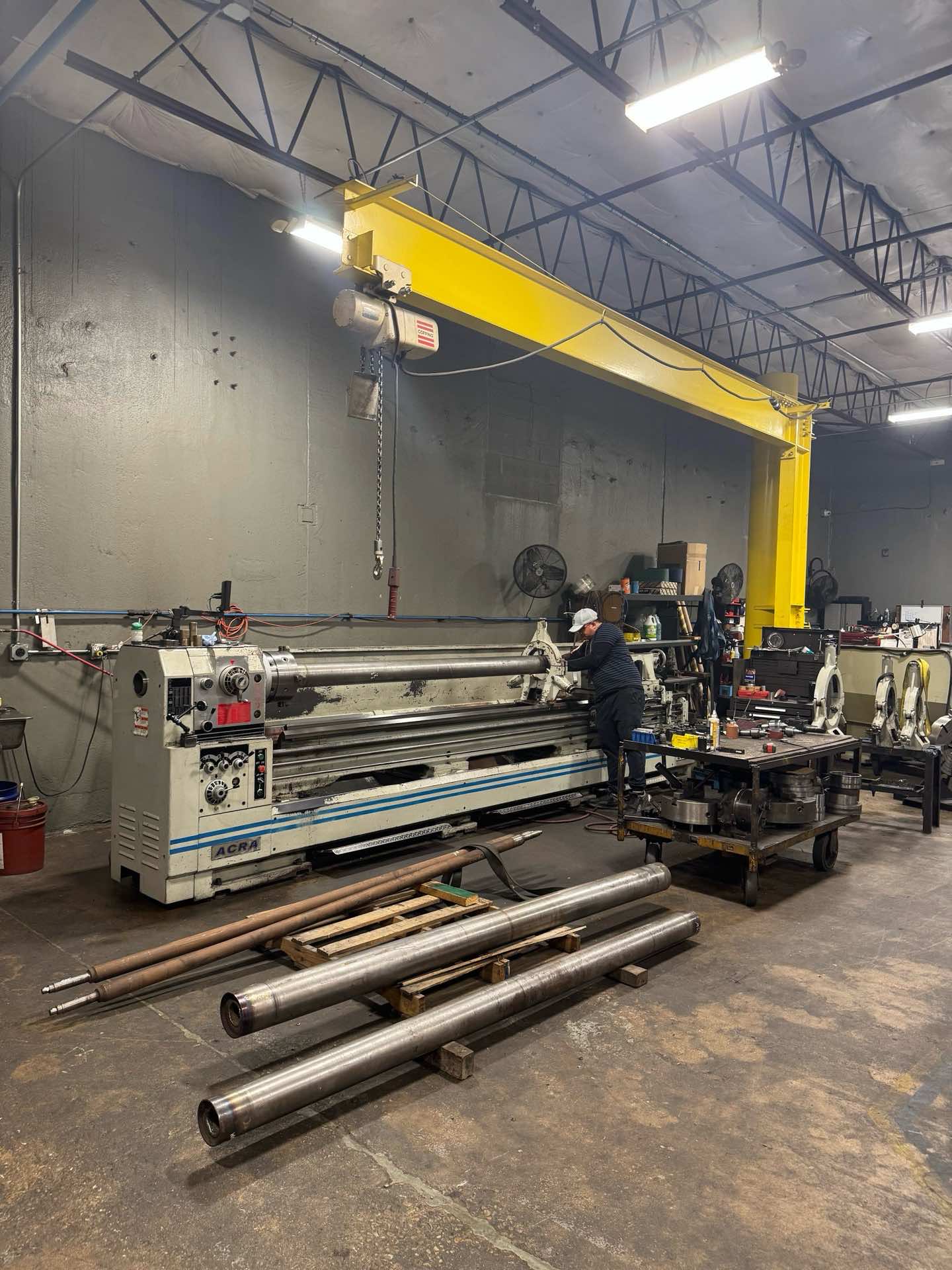 Machinist working a long shaft on a lathe beneath the jib crane at Kimbrell Manufacturing Corporation