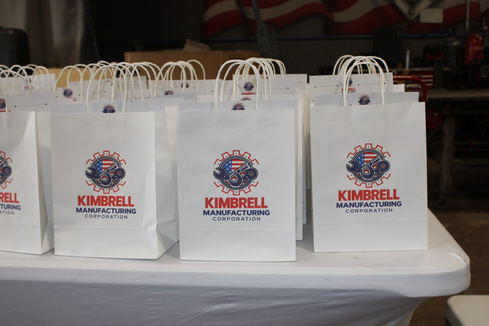 Rows of white Kimbrell Manufacturing gift bags on a table