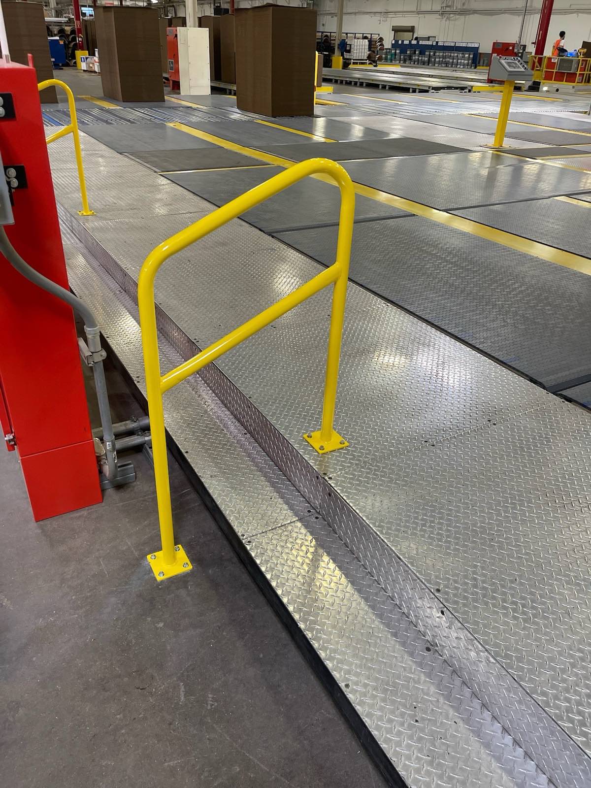 Yellow safety handrails on a diamond-plate platform installed at a customer facility