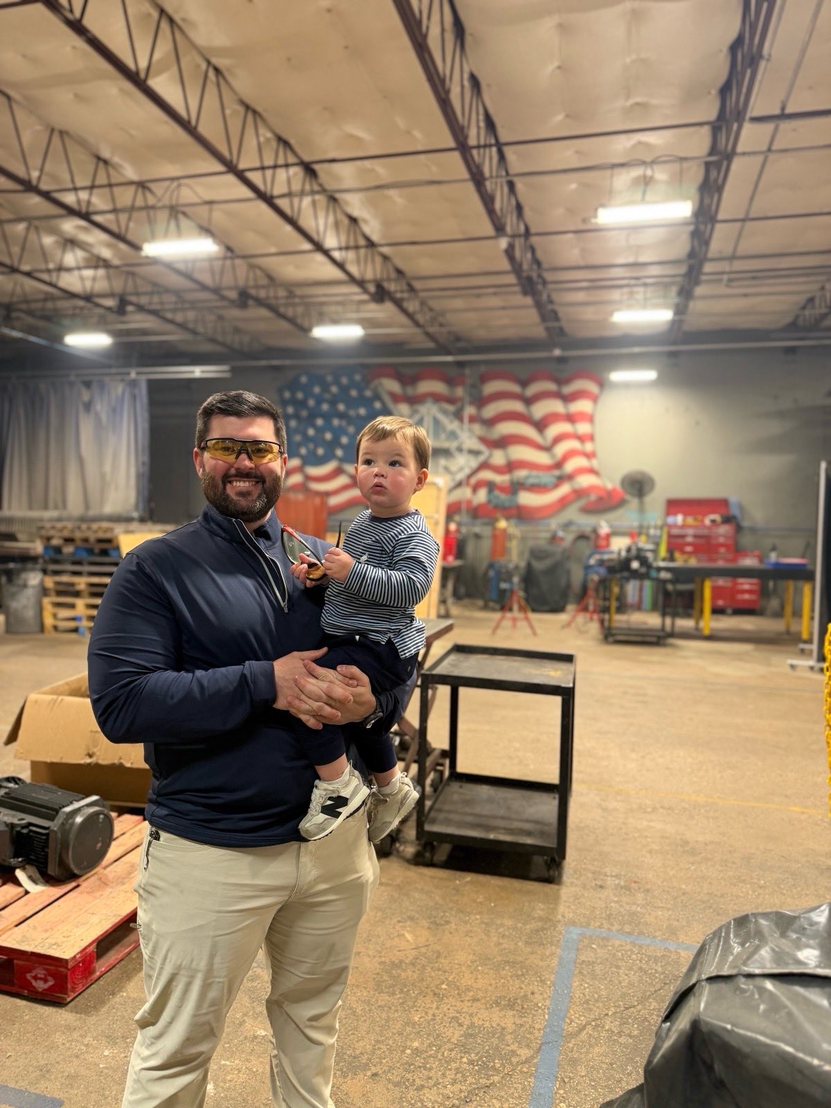Owner holding his young son inside the Kimbrell Manufacturing Corporation facility in Garland, Texas
