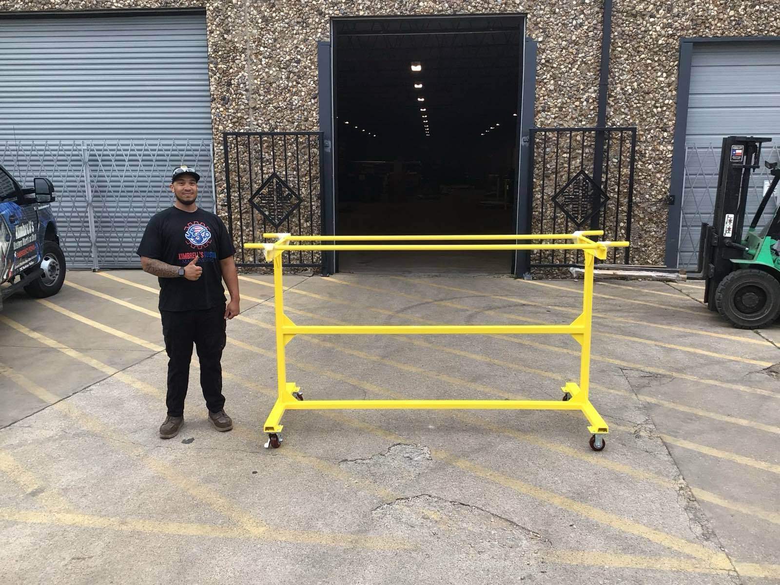 Kimbrell team member with a completed yellow fabricated rail cart outside the Garland shop