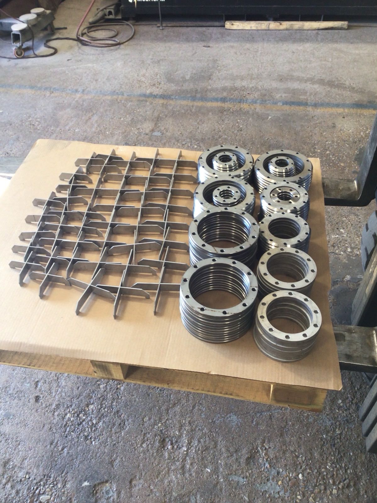 Production run of machined flanges and a waterjet-cut baffle grid staged on a pallet at Kimbrell Manufacturing Corporation